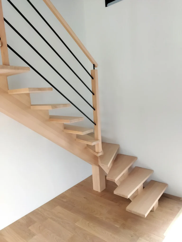 Escalier quart tournant bas limon central en hêtre, rampe Croisière barreaux noirs, intérieur contemporain posé par HALLOU ESCALIERS, à Dinard (35). Fabricant d'escaliers sur mesure