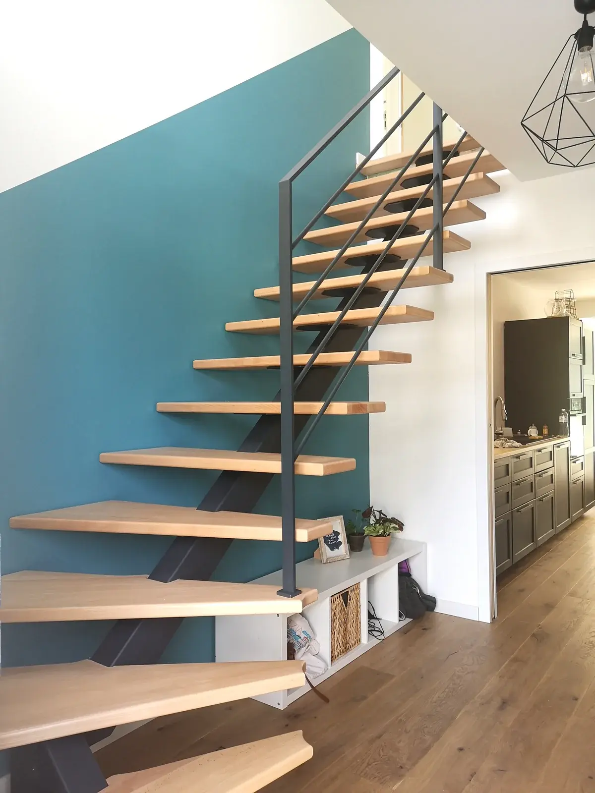 Vue de profil d'un escalier métal droit limon Paquebot en hêtre, structure acier anthracite, garde-corps acier avec barres horizontales et rangement intégré sous escalier, réalisation sur mesure HALLOU ESCALIERS à Cesson-Sévigné (35). — HALLOU ESCALIERS, Cesson-Sévigné (35).