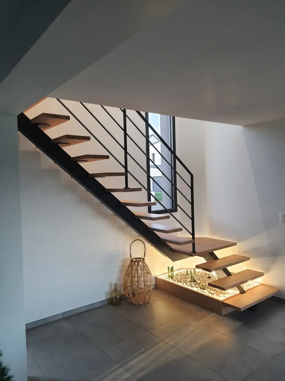 Vue diagonale de dessous d'un escalier métal droit limon Paquebot en acier noir thermolaqué, marches en hêtre massif très clair, garde-corps barres horizontales acier et main courante bois, réalisation HALLOU ESCALIERS à Chantepie (35). — HALLOU ESCALIERS, Chantepie (35).