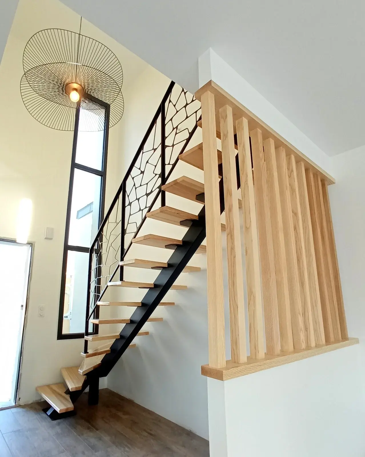 Escalier métal droit limon Paquebot en acier noir thermolaqué, marches en chêne massif, garde-corps Écaille en tôle découpée motif galets organiques, avec garde-corps de palier à balustres bois, réalisation HALLOU ESCALIERS à Vitré (35). — HALLOU ESCALIERS, fabricant d'escaiers - Vitré (35).