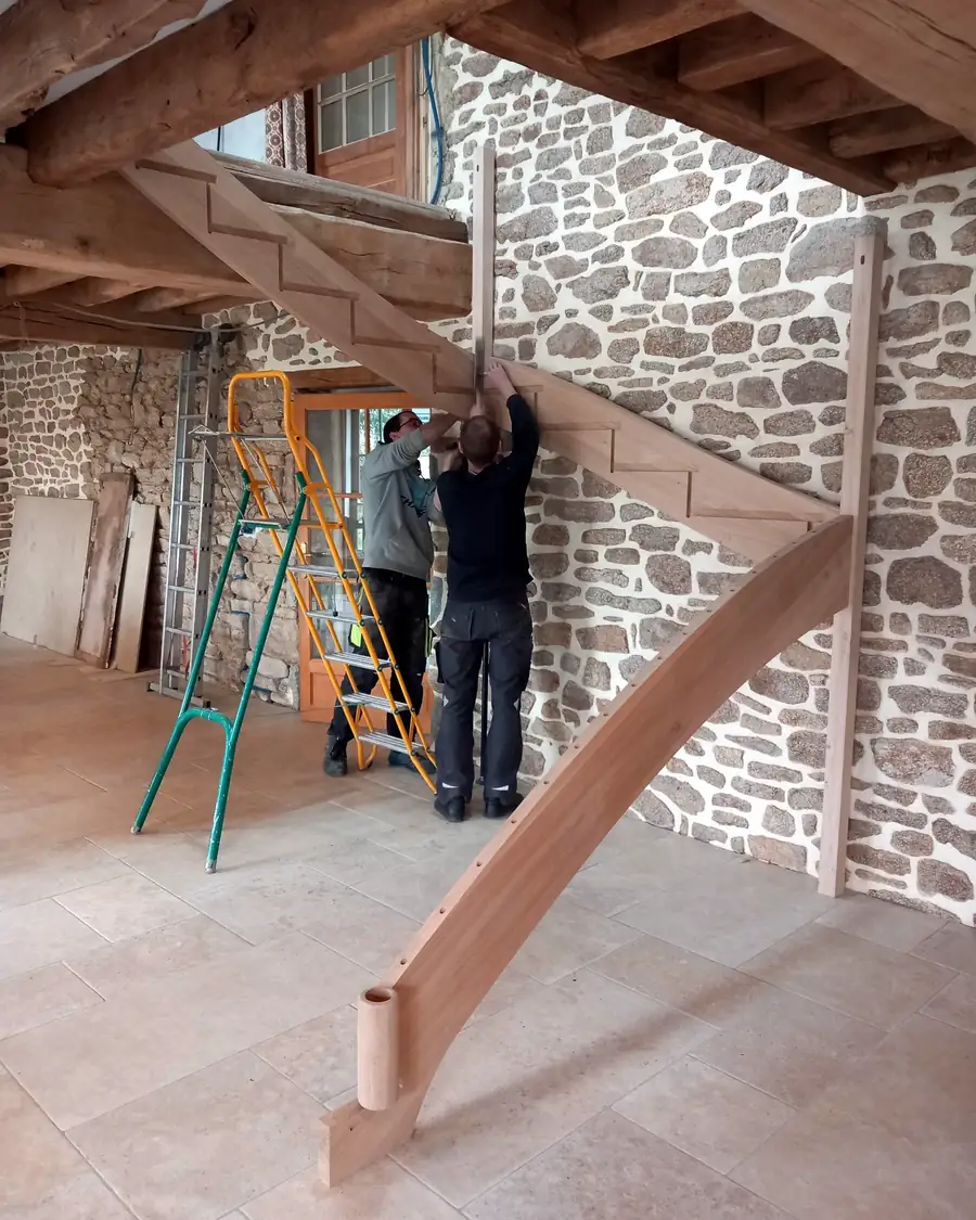 Hallou Escaliers Pose des limons d'un escalier bois quart tournant contre un mur en pierre